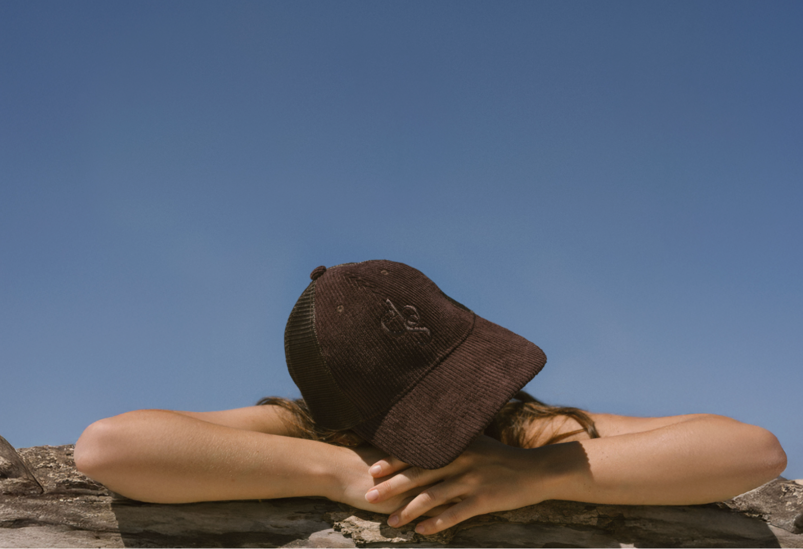 Person wearing Eco By Sonya Good Thoughts Cap against a clear blue sky.
