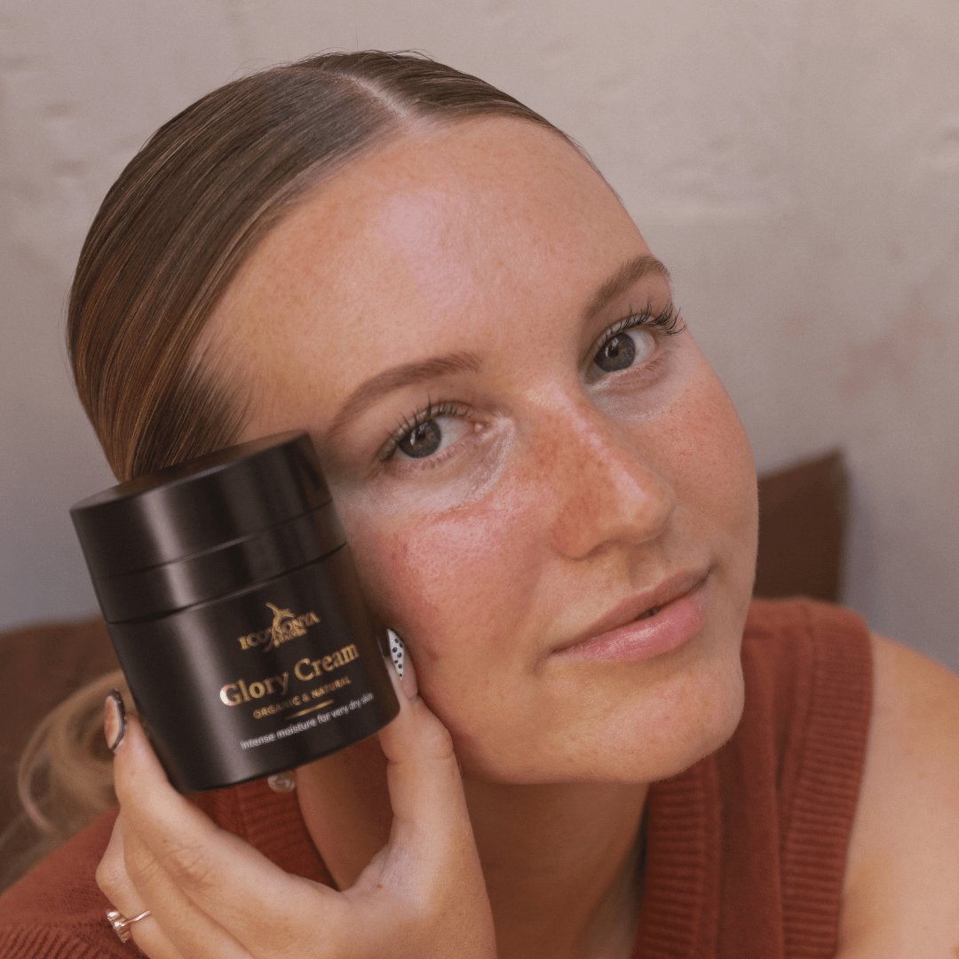 Woman holding Eco By Sonya Glory Cream jar close to her face against a neutral background, natural organic rich moisturiser.