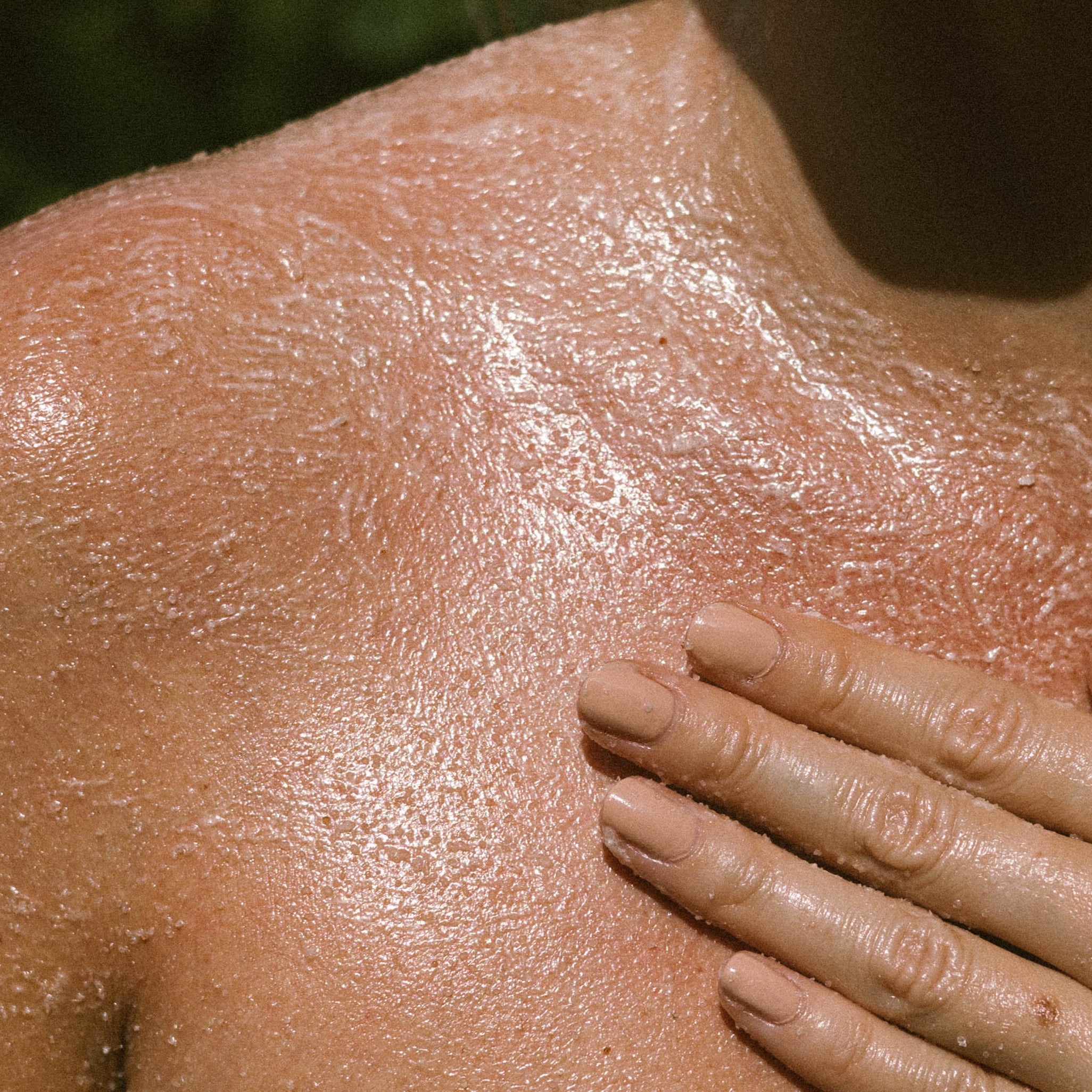 Pink Himalayan Salt Scrub body exfoliator hand closeup on decolletage and shoulder salt texture 